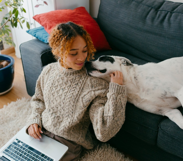 Women sitting on the ground with a laptop in her lap and a dog laying near her at our Charlotte, NC apartments for rent.